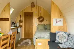 Bowcliffe pod interior with a double bed, bedding, kitchen and sofa bed