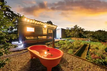 Caban Marta garden and orange wood-fired hot tub at sunset