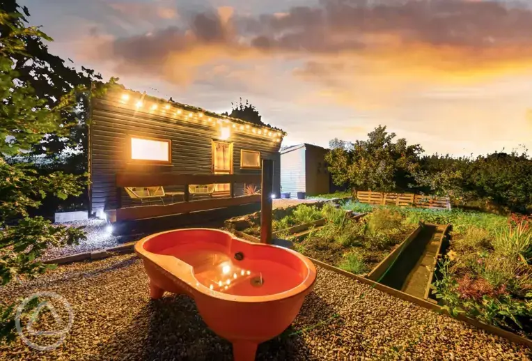 Caban Marta garden and orange wood-fired hot tub at sunset
