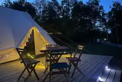 Gwenllian Emperor bell tent at night with a deck and outdoor seating Gwenllian Emperor bell tent at night with a deck and outdoor seating