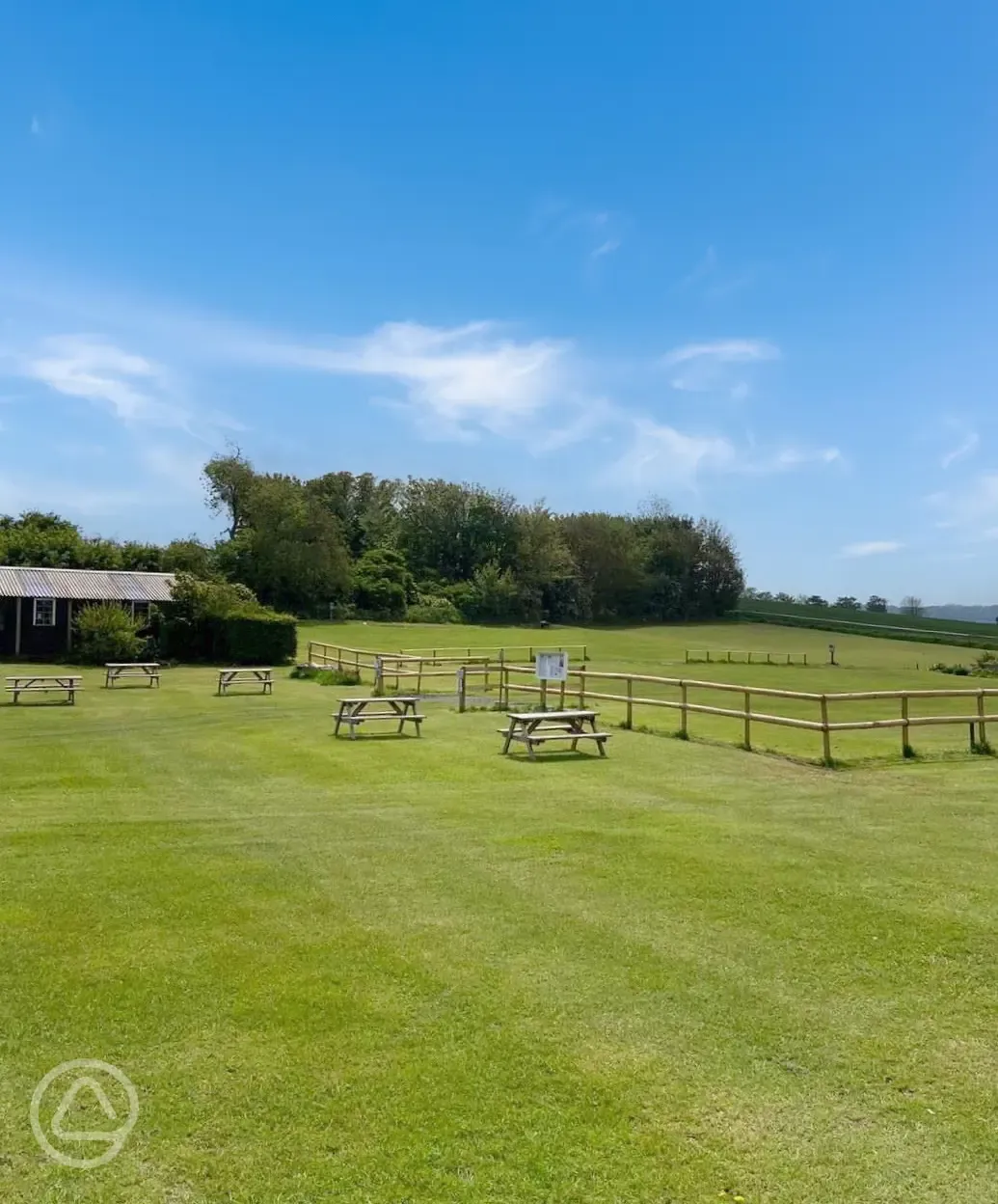 Main field with outdoor seating and the paddock behind, surrounded by trees