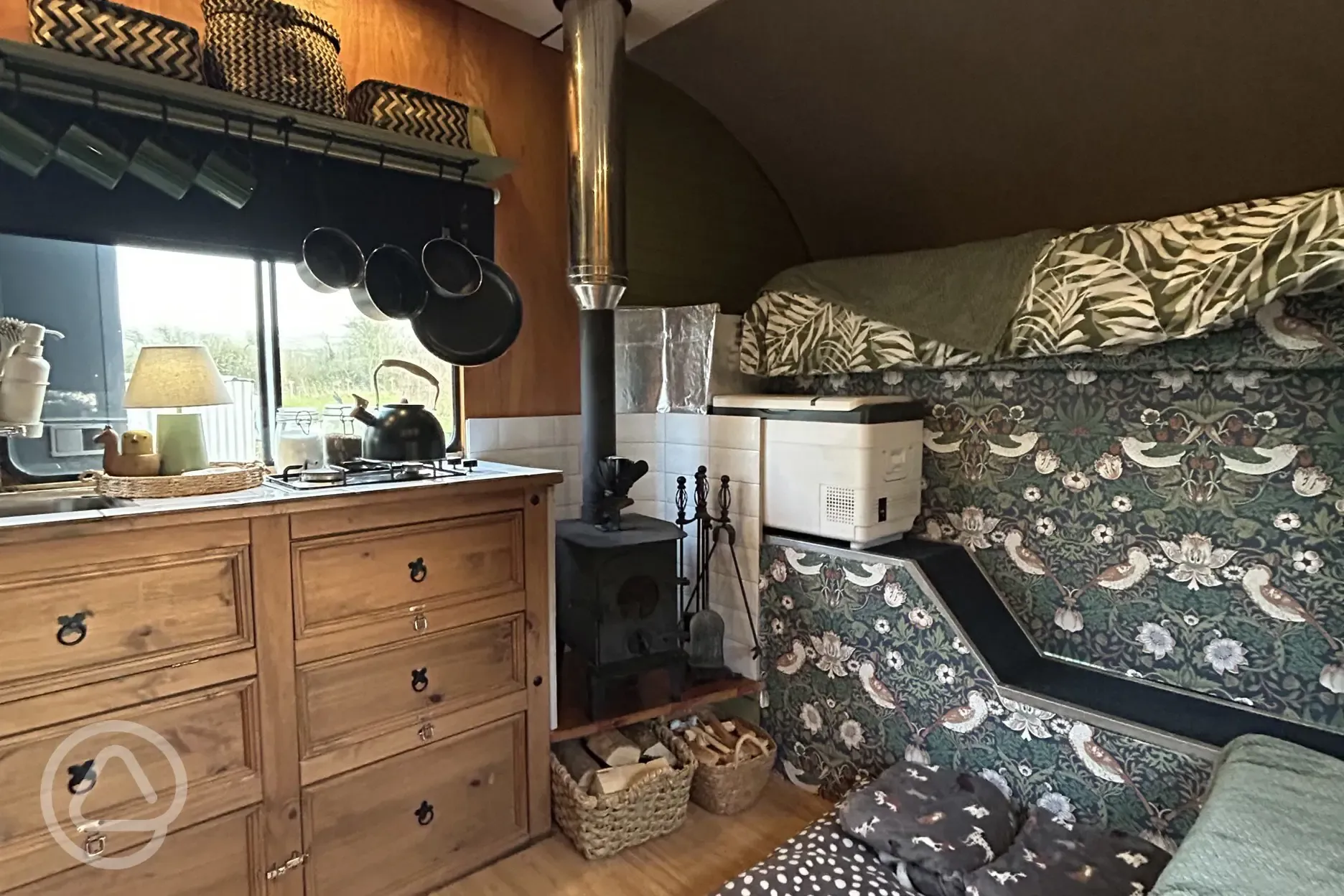 Converted horsebox living area with sofa seating and a log burner
