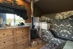 Converted horsebox living area with sofa seating and a log burner