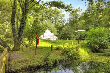 The Island bell tent with a picnic table and fire pit (accessed by a footbridge)