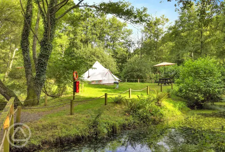 The Island bell tent with a picnic table and fire pit (accessed by a footbridge)