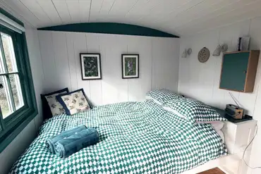 Oak shepherd's hut double bed with bedding provided at Stubbs Bridge Woodland