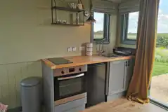 Shepherd's hut kitchen with a sink, oven, hobs, a fridge, cutlery and crockery