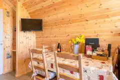 Glamping pod dining area with table, four chairs and tv