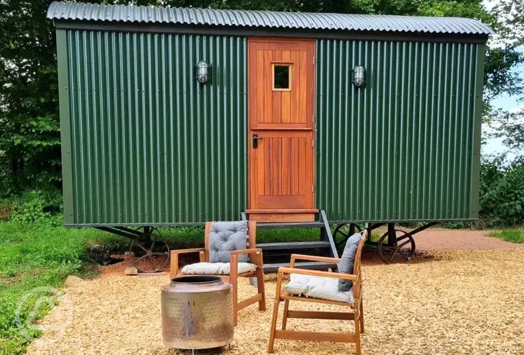 Shepherd's hut with outdoor seating and a fire pit