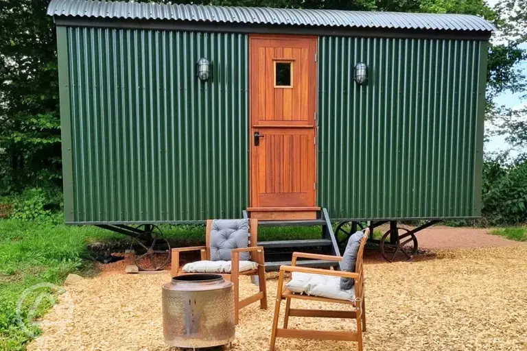 Shepherd's hut with outdoor seating and a fire pit