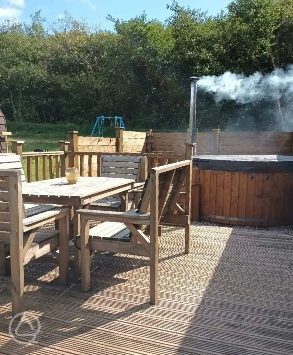 Hot tub and outdoor seating with swing set in background