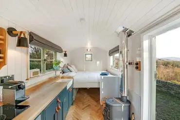 Shepherd's hut interior with a fold down double bed, wood burner and kitchen