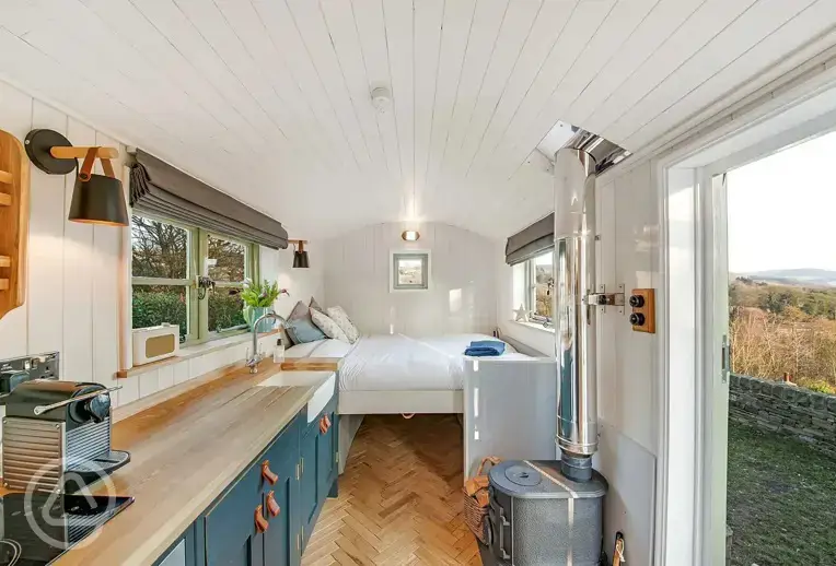 Shepherd's hut interior with a fold down double bed, wood burner and kitchen