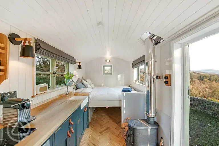 Shepherd's hut interior with a fold down double bed, wood burner and kitchen