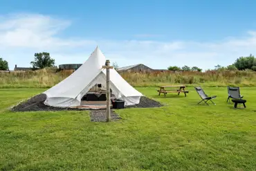 Furnished bell tents with a private fire pit, solar lights, and picnic bench