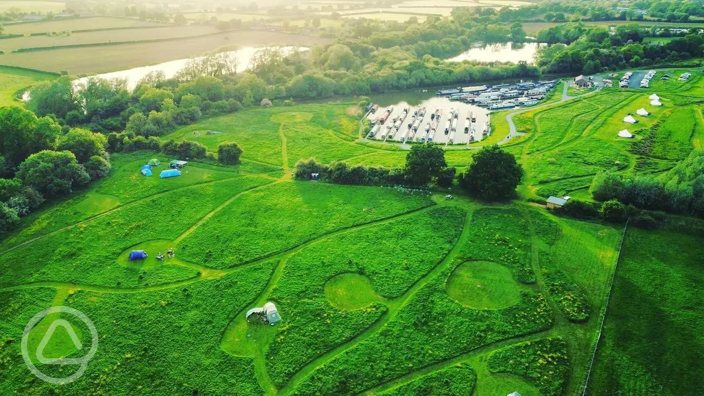 Aerial of grass pitches and bell tents beside Oakwood Marina