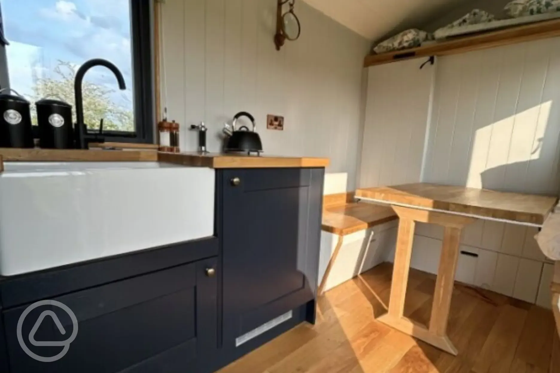 Kitchenette in shepherd's hut with a kettle, fridge, and cooking space