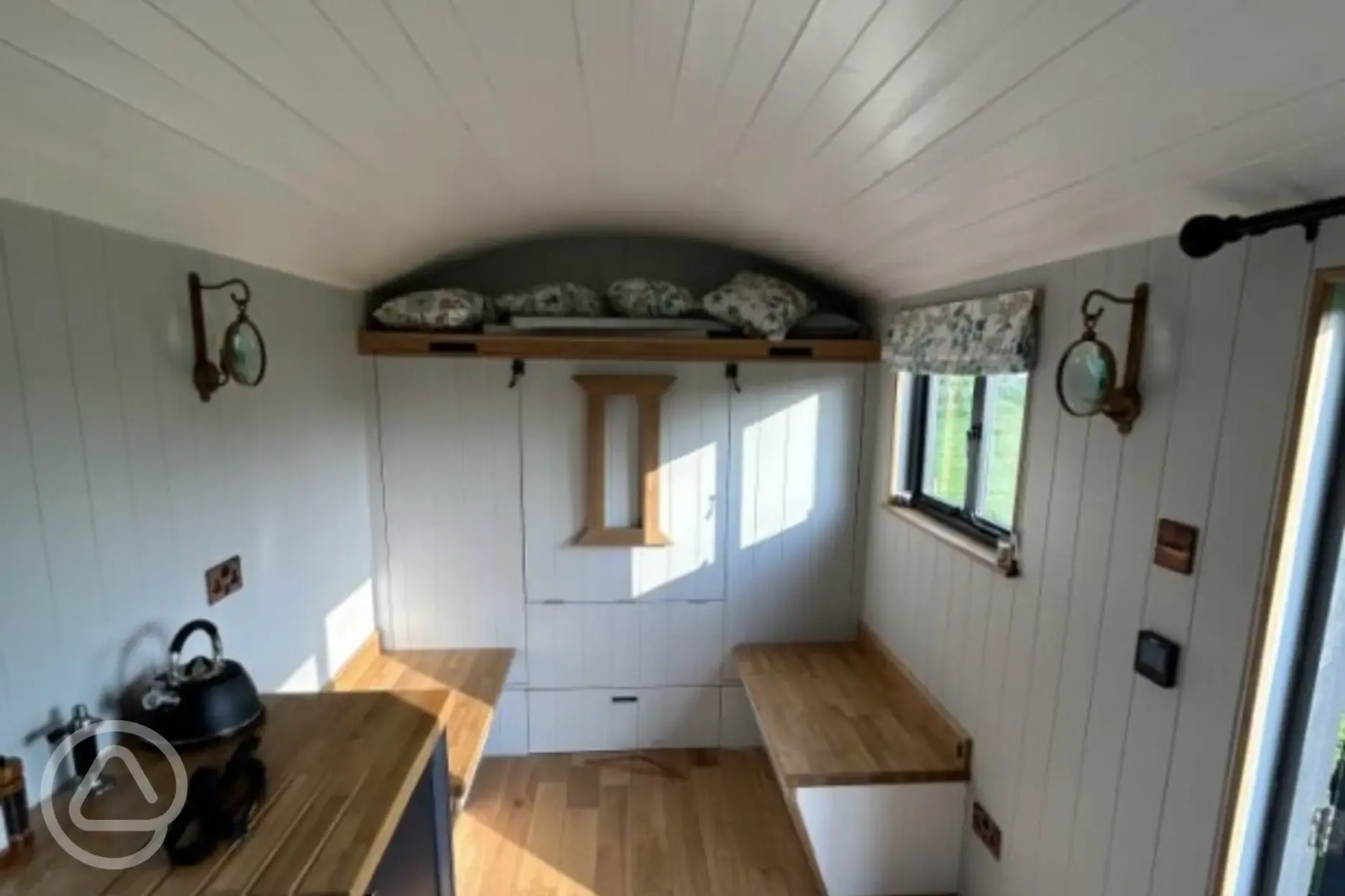 Double bed folded up for storage area and seating in shepherd's hut