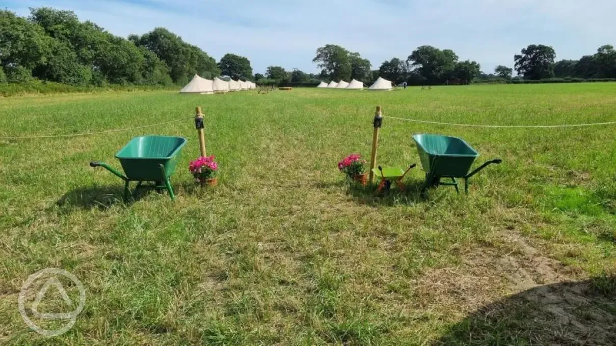 Bell tent field with wheelbarrows to transport to your pitch