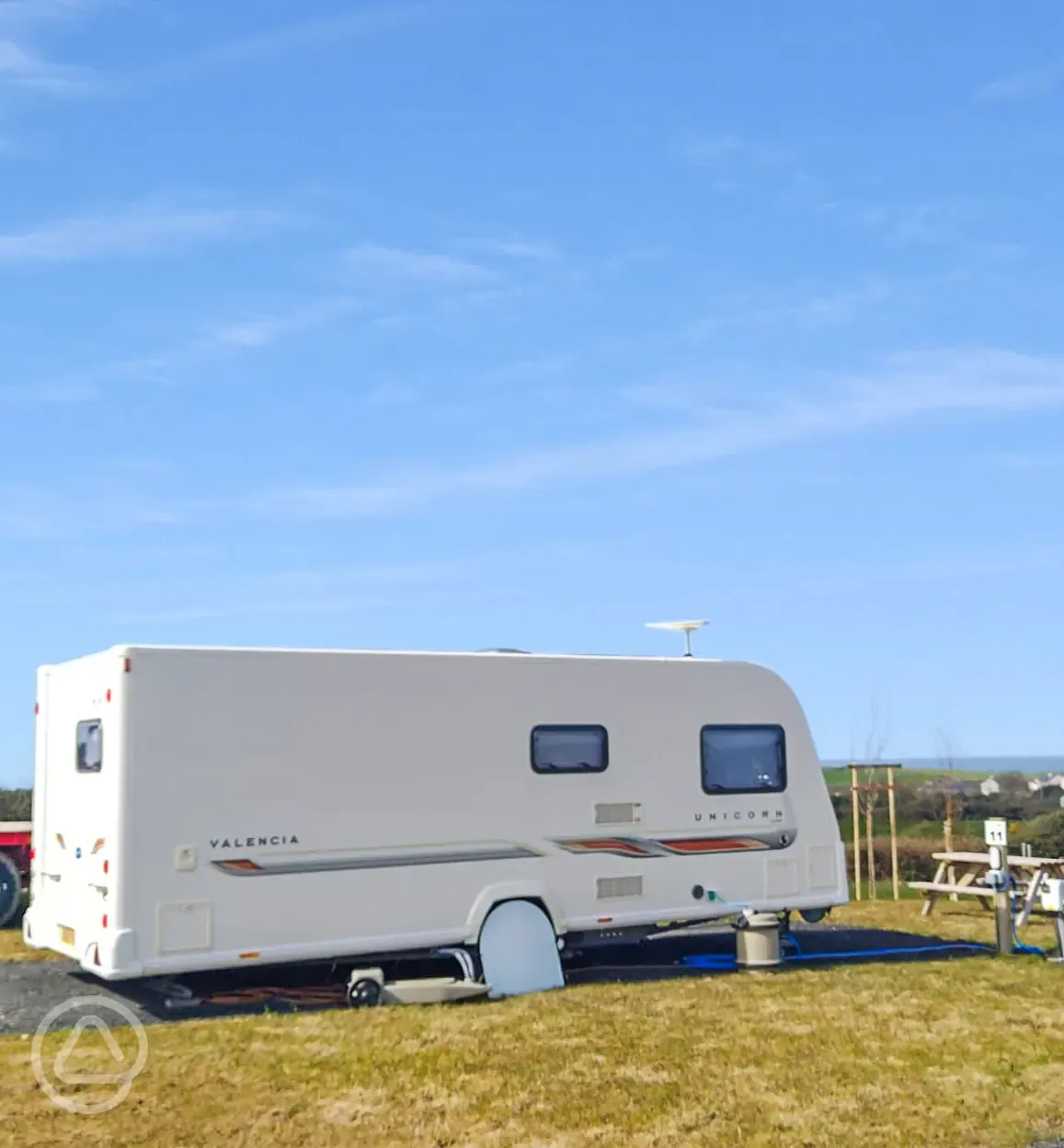 Caravan on a grass and hardstanding touring pitch with optional electric