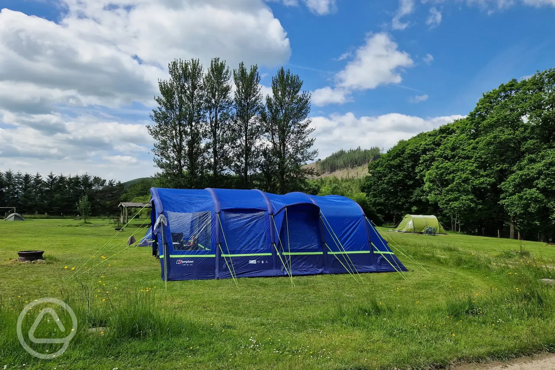 Fire pit infront of a large grass tent pitch 