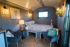 Shepherd's hut interior with a queen size bed with bedding