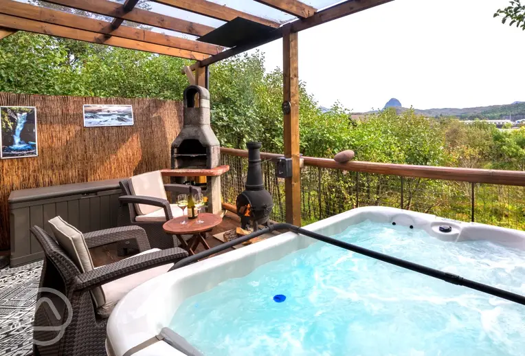 Private outdoor area with a BBQ, a chimenea and a hot tub with waterside views