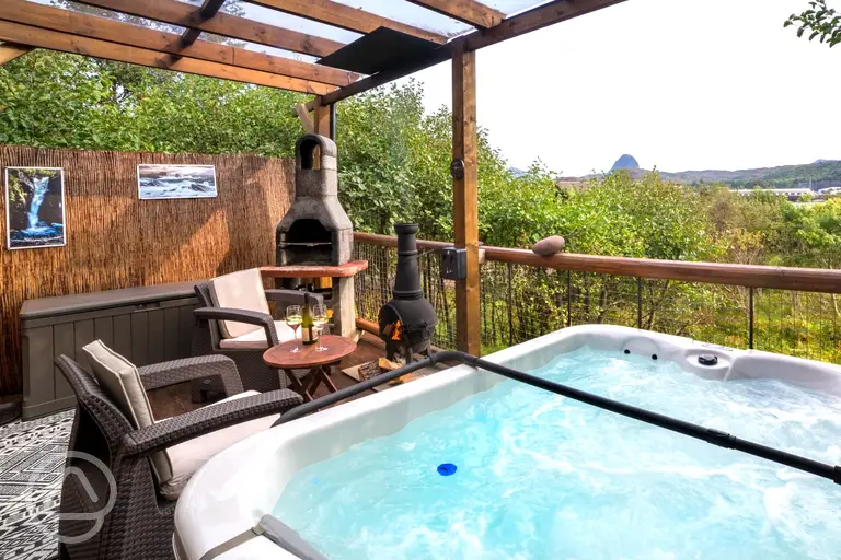 Private outdoor area with a BBQ, a chimenea and a hot tub with waterside views