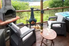 Private outdoor area with a BBQ, a chimenea and a hot tub with waterside views