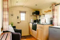 Noddfa shepherd's hut kitchen with a fridge, cooker, microwave and hob Noddfa shepherd's hut kitchen with a fridge, cooker, microwave and hob