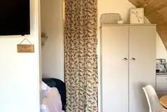 Pod interior with a double bed, dining area, TV and dividing curtain