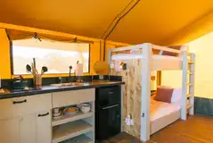 Family safari tent with an open-plan interior with a kitchen and bunk beds