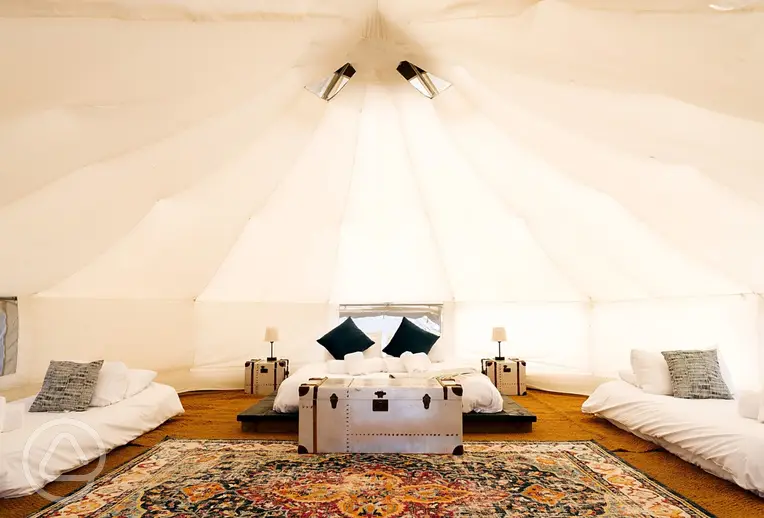 Bell tent interior with a double bed and three single beds with bedding