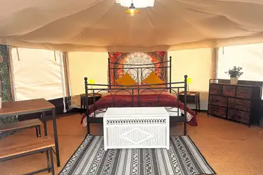 Yurt interior at Old Park Cottage Camping with a king sized bed and furniture
