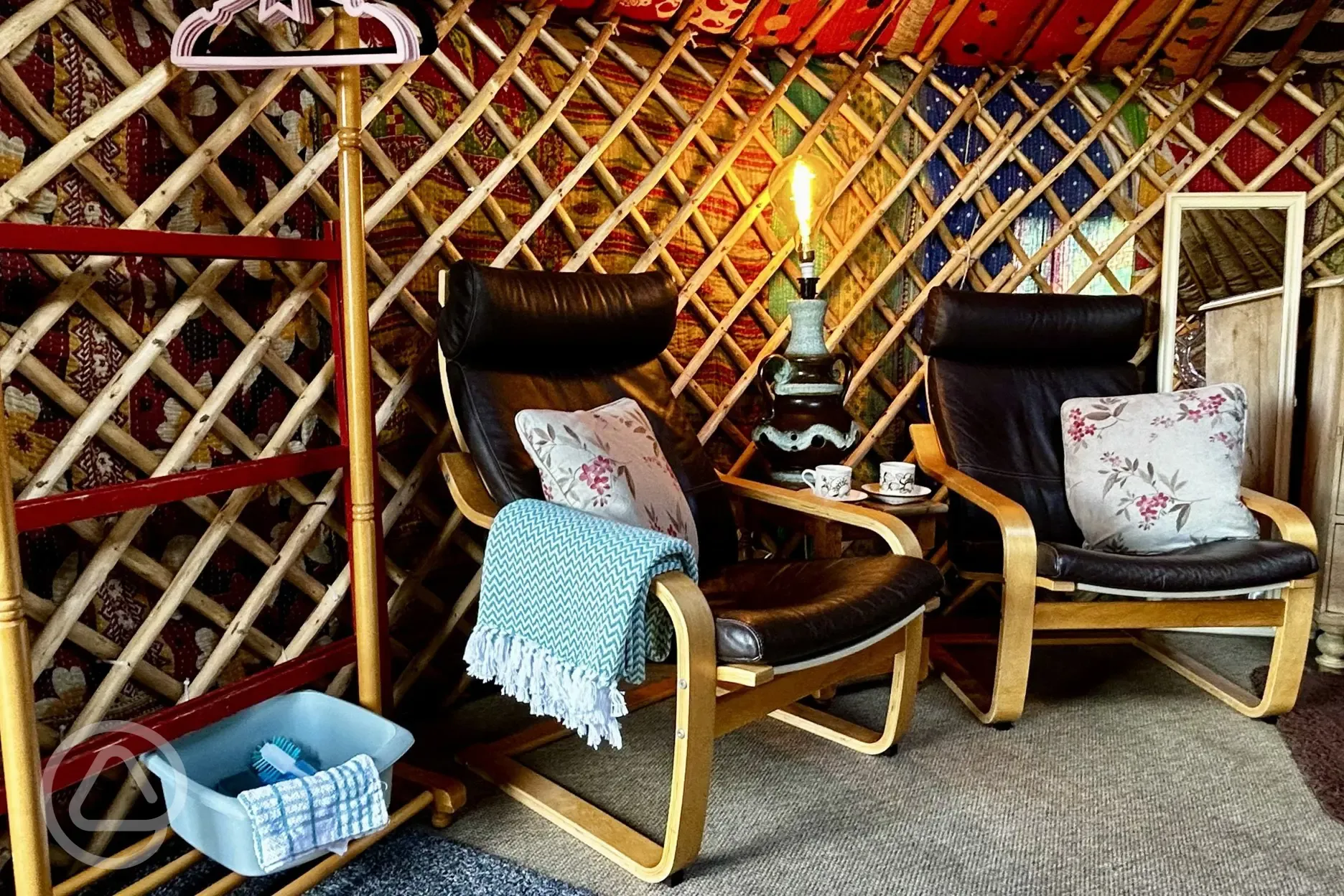 Primrose Yurt seating area with blankets and a clothes rail with hangers