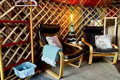 Primrose Yurt seating area with blankets and a clothes rail with hangers