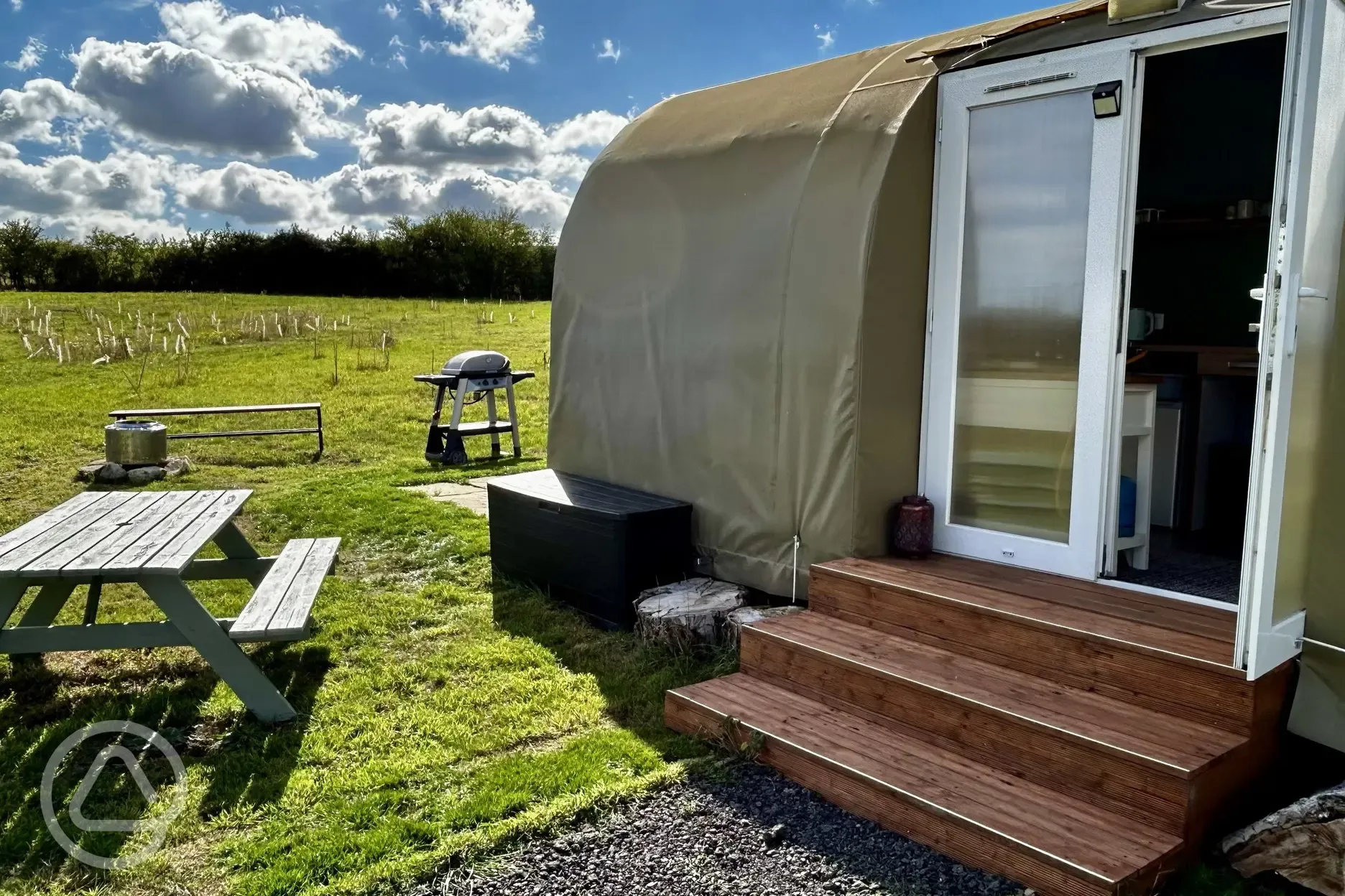 Coco Pod exterior with picnic bench, fire pit, and BBQ