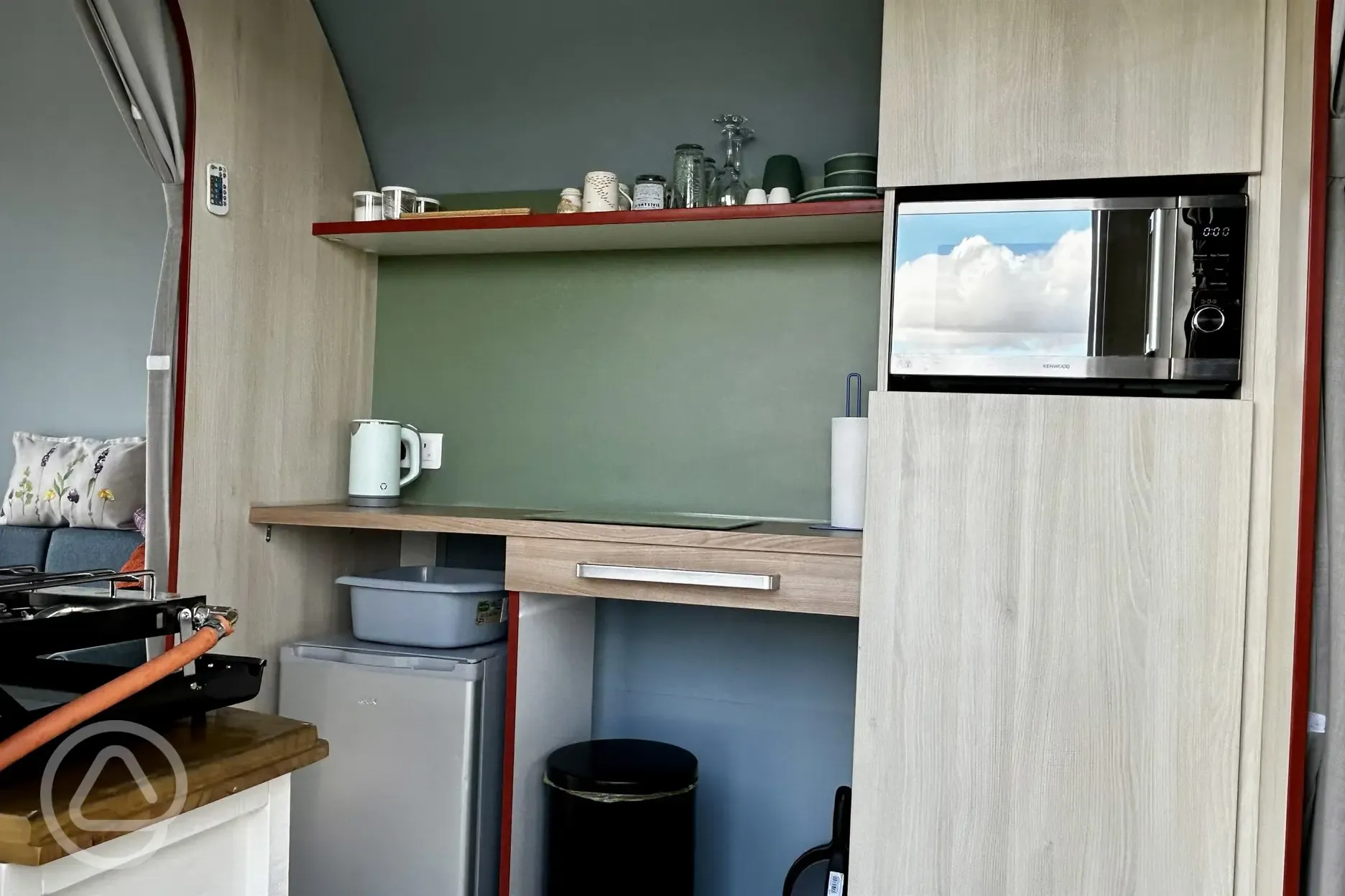 Coco Pod campers kitchen with fridge, kettle, microwave, and utensils