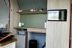 Coco Pod campers kitchen with fridge, kettle, microwave, and utensils
