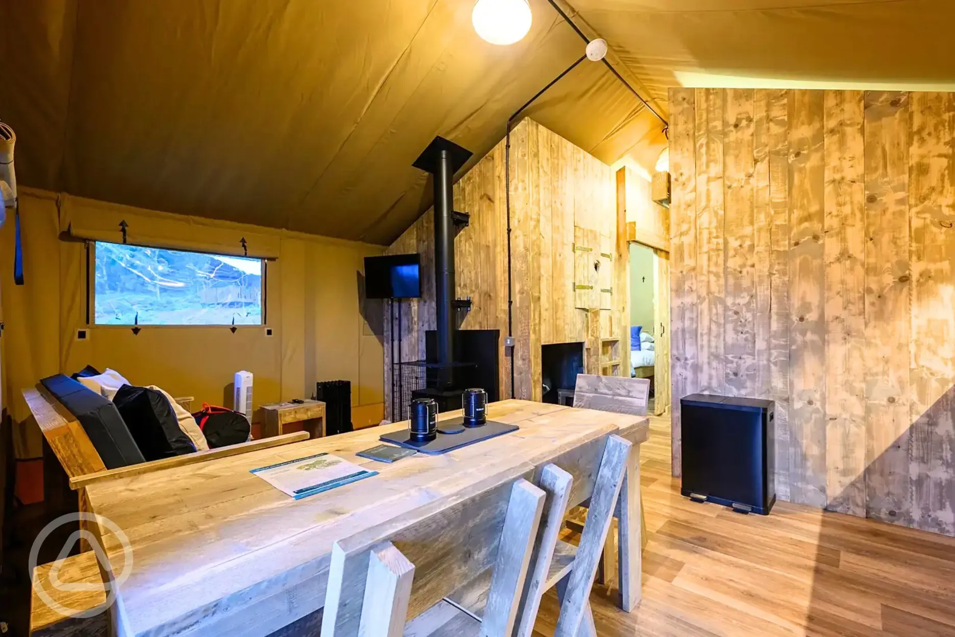 Deluxe Safari Tent interior with a wood burner, TV, dining area and kitchen