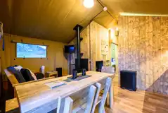 Deluxe Safari Tent interior with a wood burner, TV, dining area and kitchen