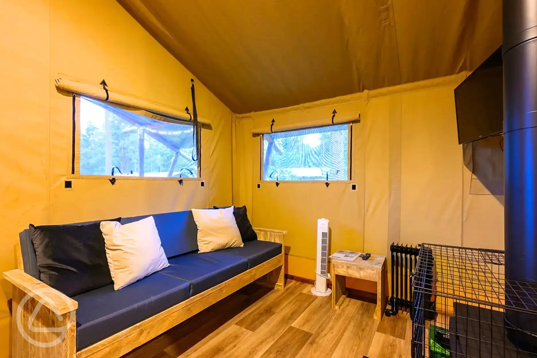 Premium Safari Tent interior with a sofa, wood burner and TV