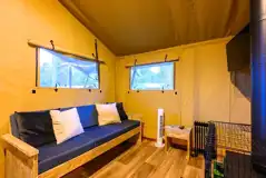 Premium Safari Tent interior with a sofa, wood burner and TV