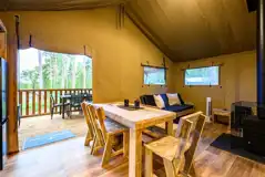 Premium Safari Tent interior with a sofa, wood burner, TV and dining area