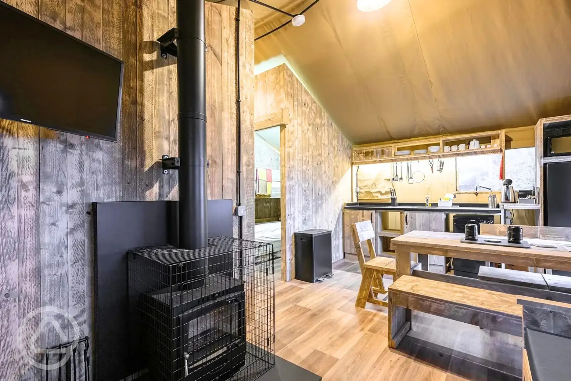 Deluxe Safari Tent interior with a wood burner, TV, dining area and kitchen