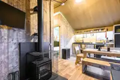 Deluxe Safari Tent interior with a wood burner, TV, dining area and kitchen