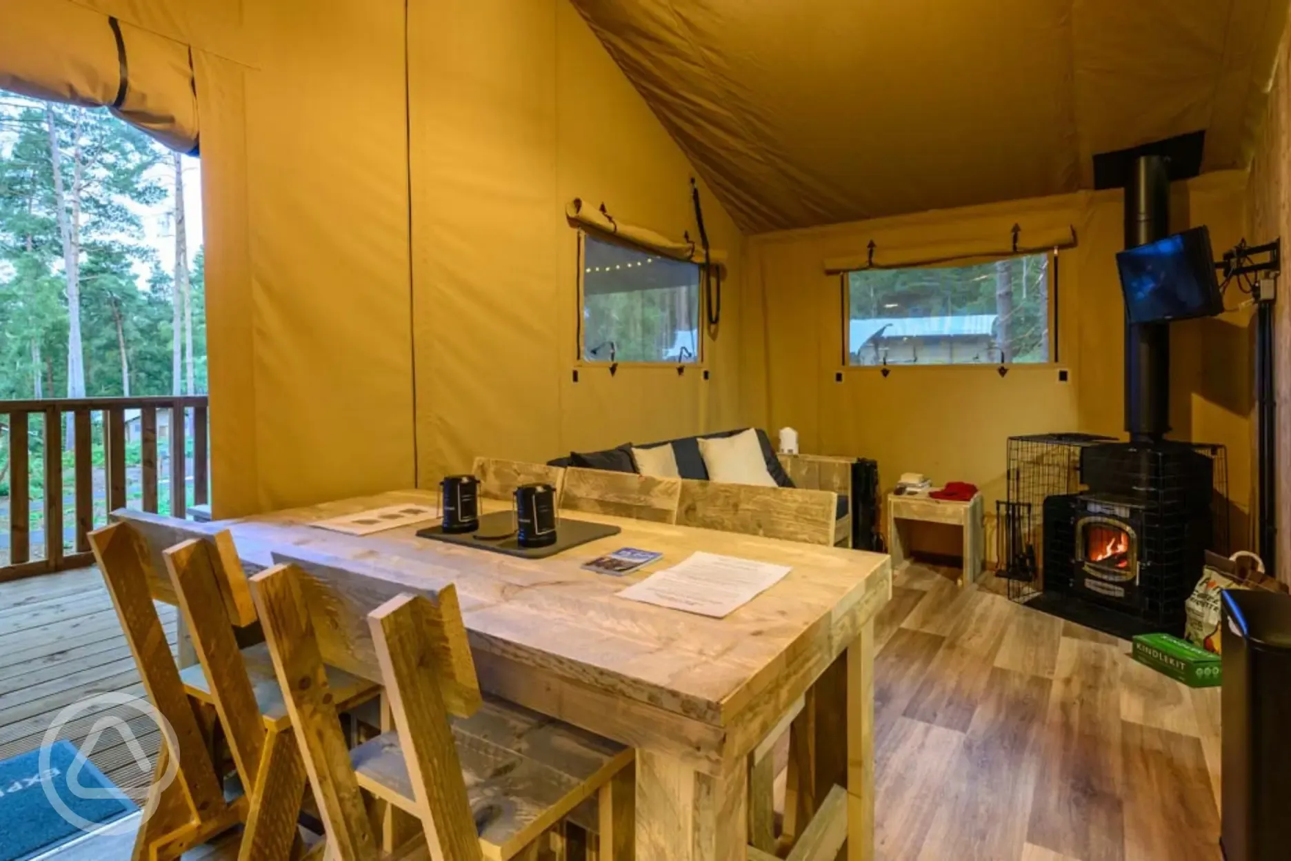Premium Safari Tent interior with a sofa, wood burner, TV and dining area