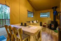 Premium Safari Tent interior with a sofa, wood burner, TV and dining area