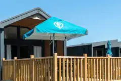 Superior glamping cabins with an outdoor deck, furniture and parasol