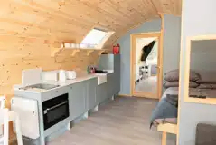Glamping pod interior with a double bed, double sofa bed and kitchenette